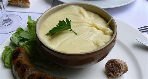  Aligot: Een romige aardappelpuree met geraspte kaas en knoflook die je smaakpapillen zal verwennen!